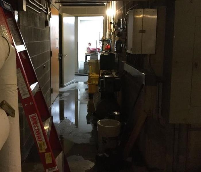water covers a concrete floor in the basement level of a commercial building